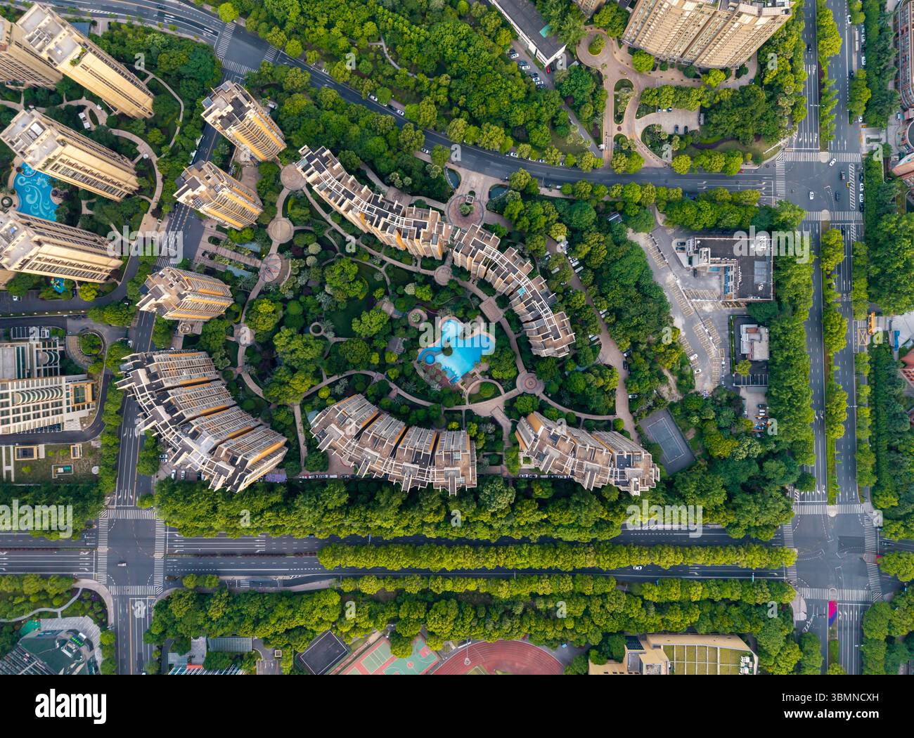 Aerial view of a densely populated residential neighborhood featuring modern buildings surrounded by lush greenery. Stock Photo