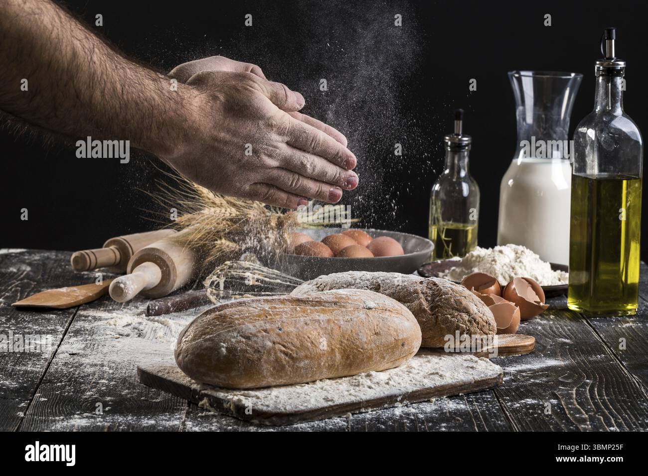 Chef sprinkles fresh bread with flour. Man preparing dough at table in ...