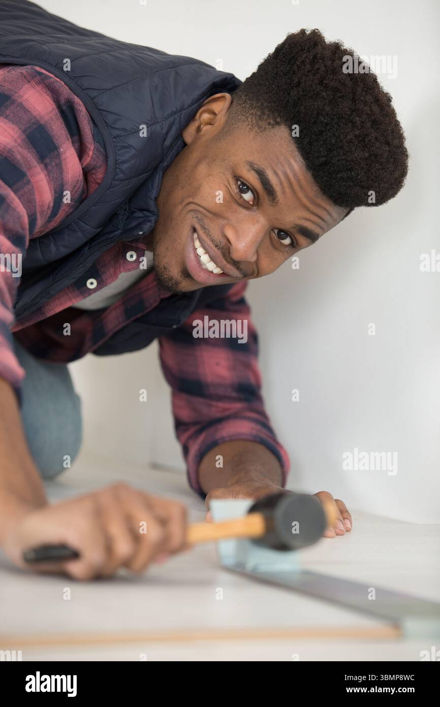 young man using hammer to knocking in flooring Stock Photo