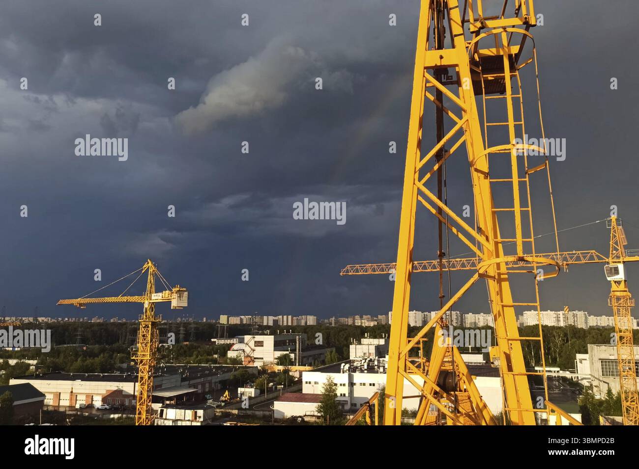 Tower cranes against the sky with clouds and rainbow Stock Photo - Alamy