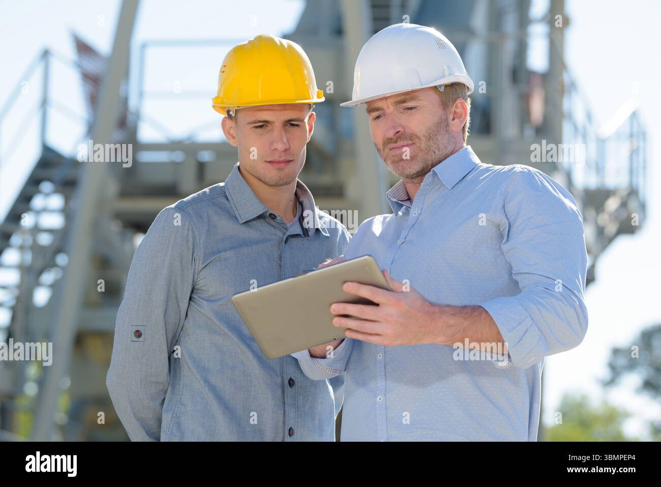 male construction workers discussing over digital tablet Stock Photo