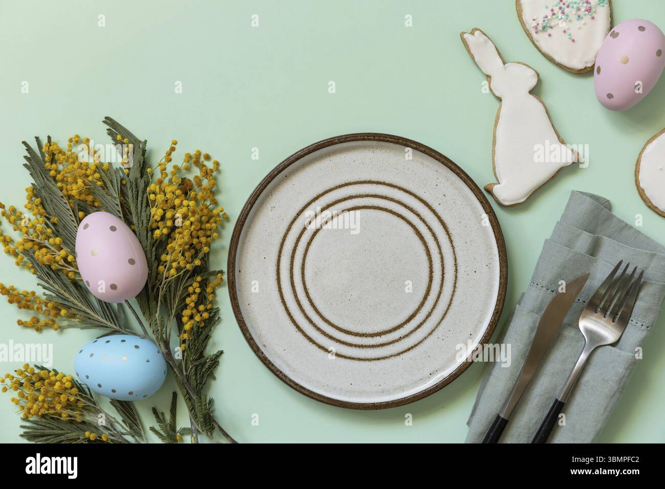 Table setting for Easter dinner with easter eggs and mimosa on a pastel background. Easter decorations concept. View from above. Copy space Stock Photo