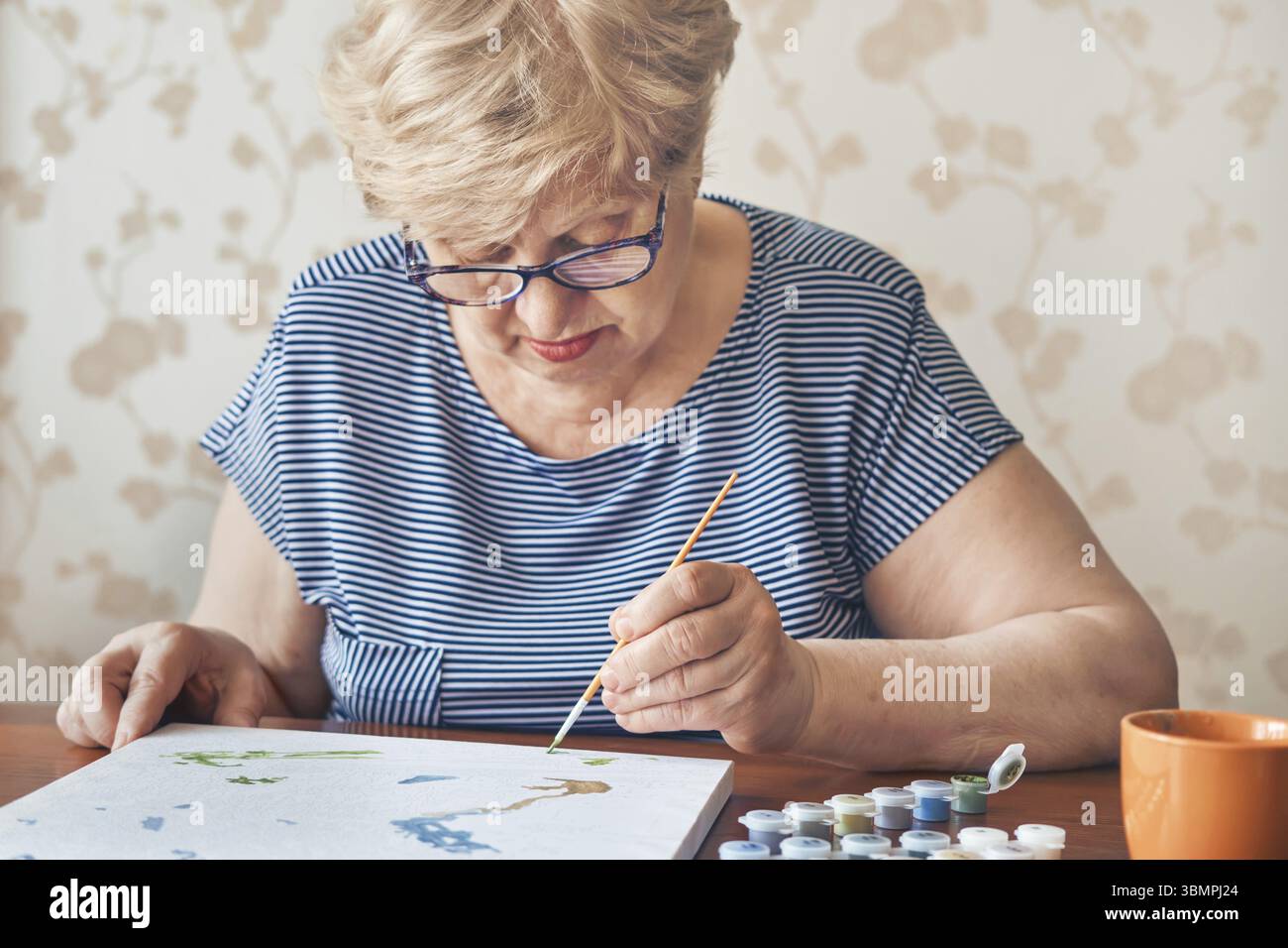 Attraktive alte Frau Malerei nach Zahlen zu Hause. Inspirations-Hobby und Kunsttherapie. Selective focus Stock Photo