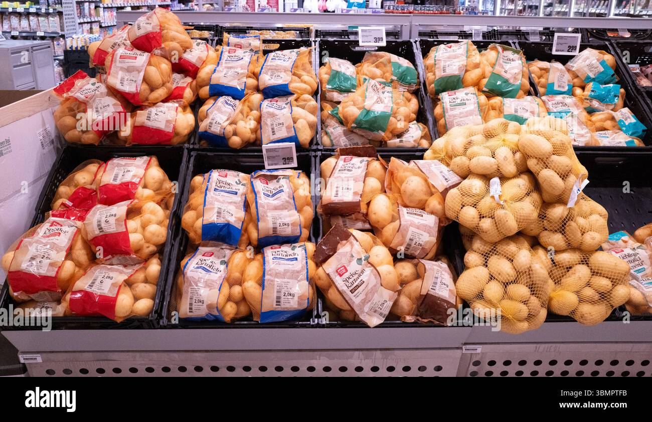 Altshausen Sortiment abgepackter Speisekartoffeln im Supermarkt Verschiedene Sorten Speisekartoffeln in 2-kg- und 5-kg-Netzen auf der Verkaufsfläche eines Supermarkts. Die abgepackten Kartoffeln sind deutlich etikettiert, unterteilt nach festkochend, vorwiegend festkochend und mehlig kochend. Die Etiketten zeigen Herkunft, Kochtyp und Preisetiketten über der Auslage. Die Stapelung der Netze und das klar strukturierte Regal bieten einen typischen Eindruck der Gemüseabteilung im Lebensmitteleinzelhandel. Aufgenommen in Altshausen. Eibner-Pressefoto/Eky Eibner. *** Altshausen Assortment of pre-pa Stock Photo
