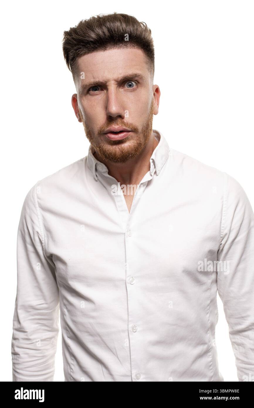 Studio photo of a good-looking man in a white shirt, looking shocked, isolated over a white background Stock Photo