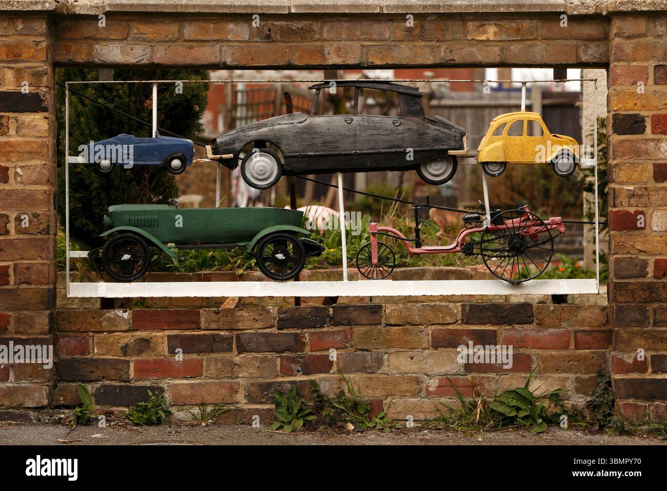 The development of the Motor Car made from metal and displayed in a garden wall, French cars. Stock Photo