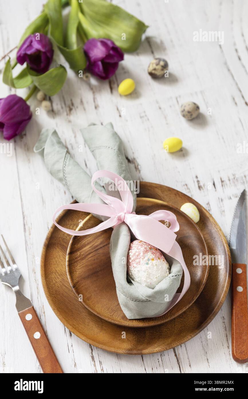 Easter table setting with painted eggs, purple tulip and cutlery on festive table. Table setting for Happy Easter day Stock Photo