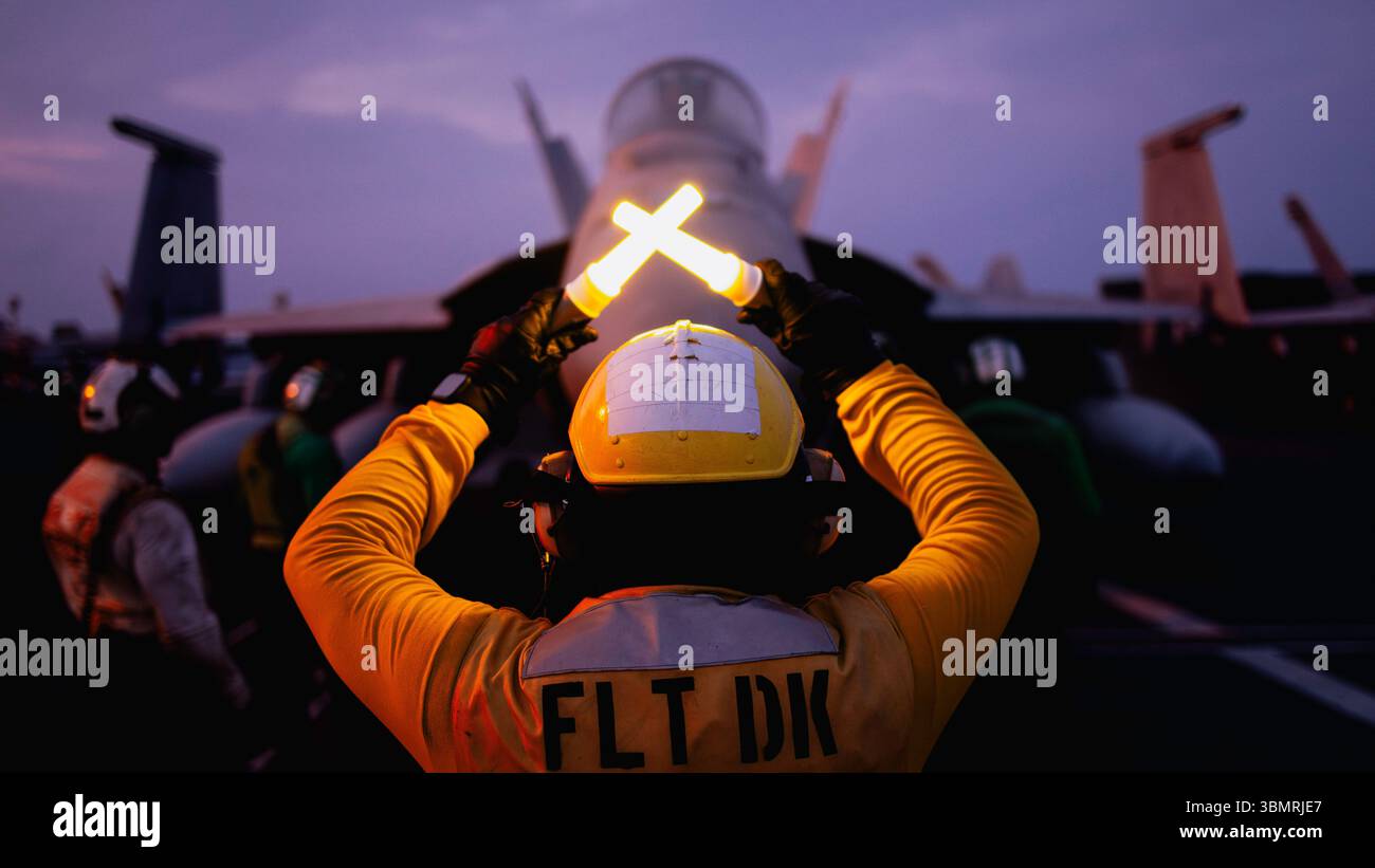 Aviation Boatswain’s Mate Aircraft Handling 1st Class Emmanuel Hernandez, from Los Angeles, assigned to air department’s flight deck crash and salvage division, directs an F/A-18E Super Hornet on the flight deck of Nimitz-class aircraft carrier USS George Washington while underway in the Philippine Sea, June 26, 2025. The USS George Washington Carrier Strike Group (GWA CSG) is on patrol in the U.S. 7th Fleet area of operations. George Washington is the U.S. Navy’s premier forward-deployed aircraft carrier, a long-standing symbol of the United States’ commitment to maintaining a free and open I Stock Photo