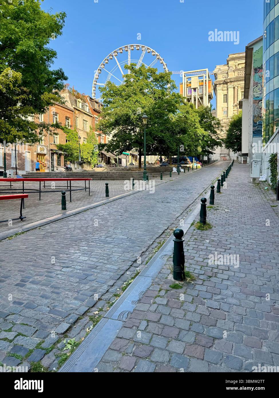 Cobblestone street with Ferris wheel and historic buildings in central Brussels, Belgium. Ideal for concepts related to tourism, urban lifestyle, etc - Smartphone Captured Stock Image