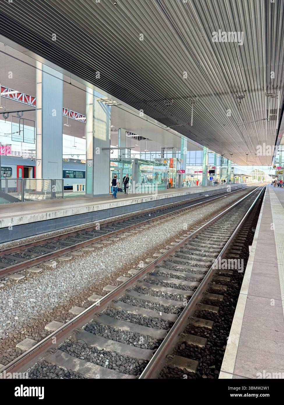 Empty railway platform at a modern train station with steel roof and parallel tracks. The image captures a quiet moment with no trains or passengers. - Smartphone Captured Stock Image
