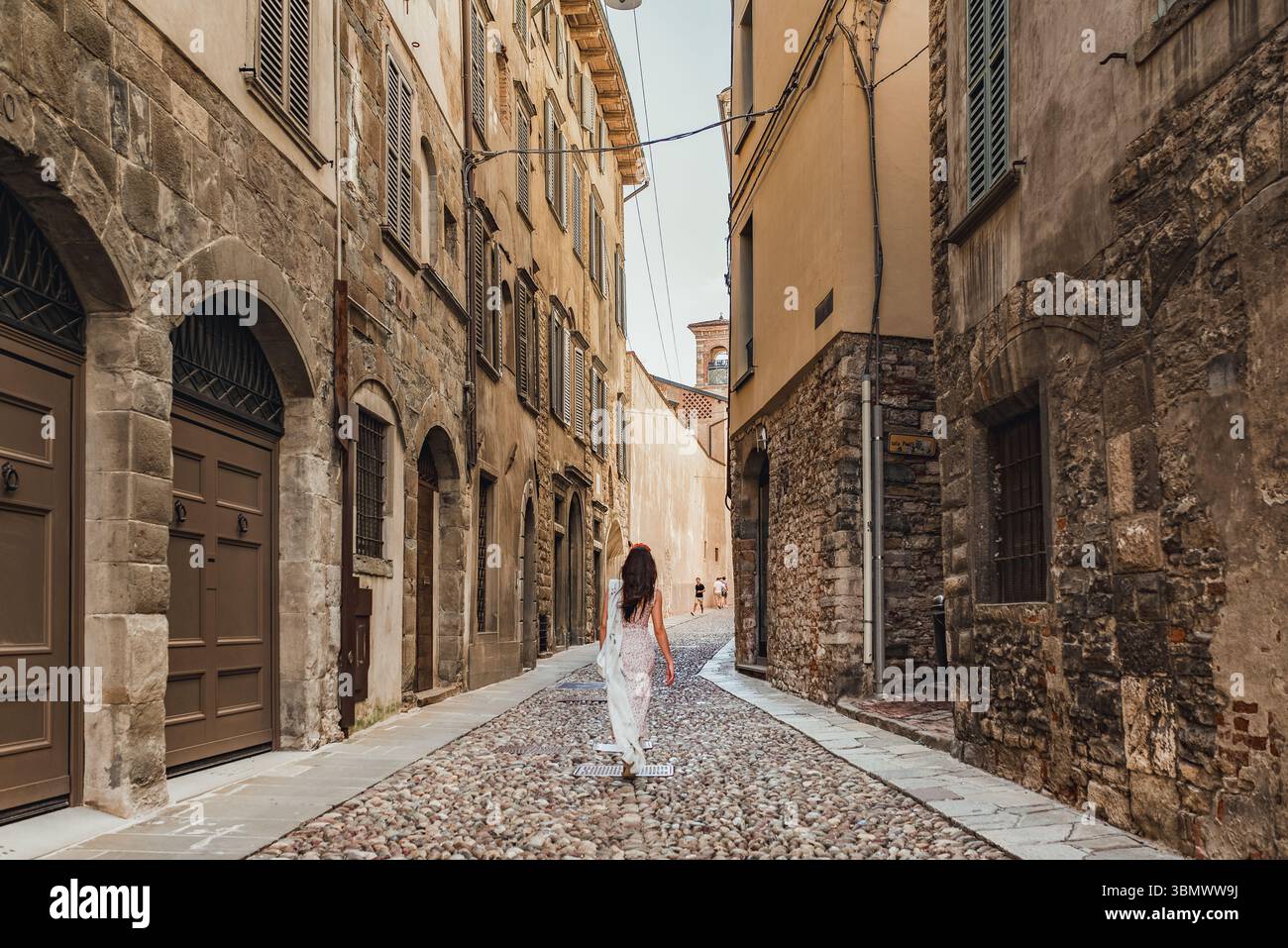 Woman walking through a narrow cobbled street in an old European town ...