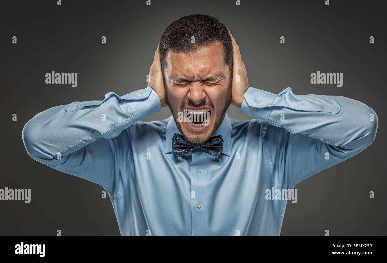 Portrait of angry upset young man in blue shirt and butterfly tie ...