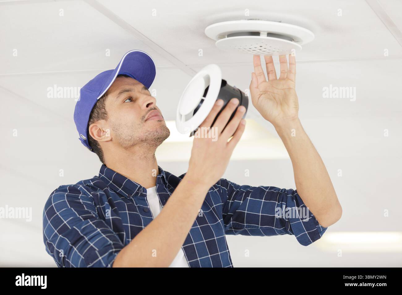 locksmith examines ventilation in the ceiling Stock Photo