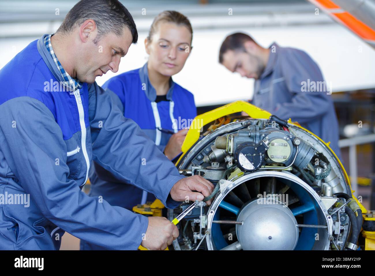 aero engineer and apprentice working on helicopter in hangar Stock Photo