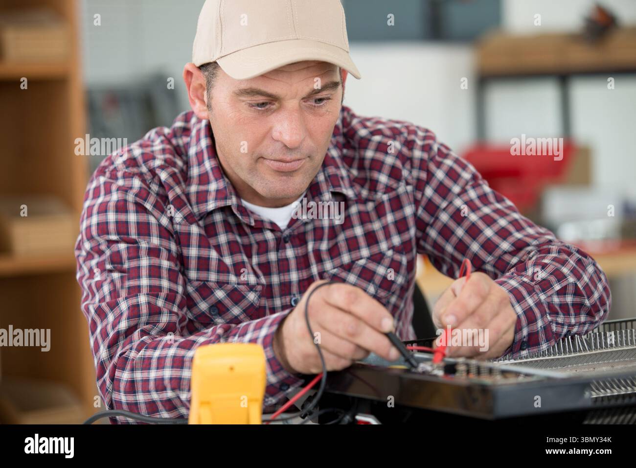 mature technician using multimeter in his workshop Stock Photo