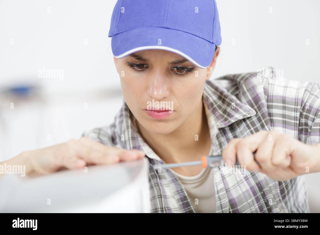 happy female builder with screwdriver fixing electric device Stock Photo