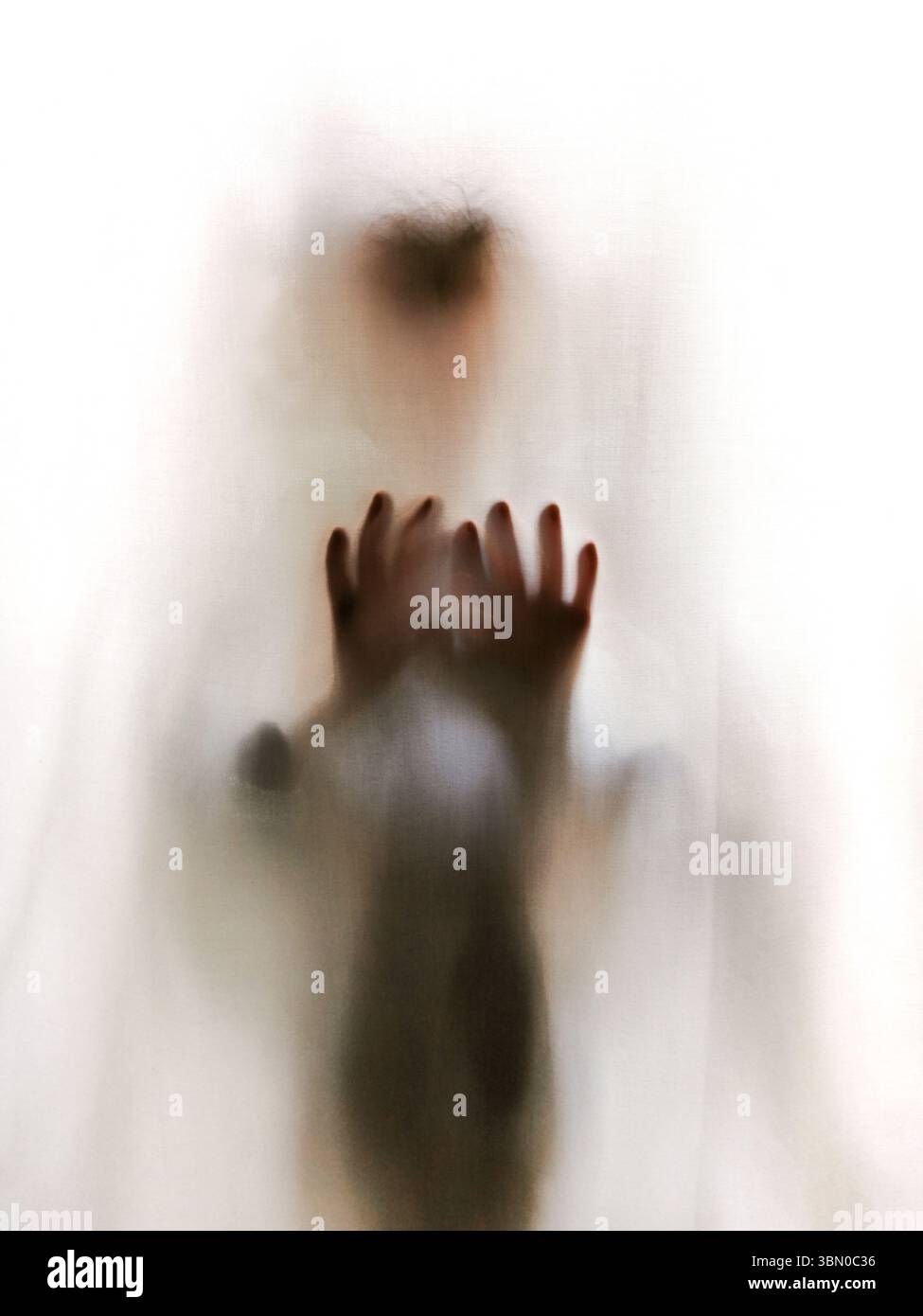 A person is seen pressing their hands against a sheer fabric, creating a haunting silhouette. - Smartphone Captured Stock Image