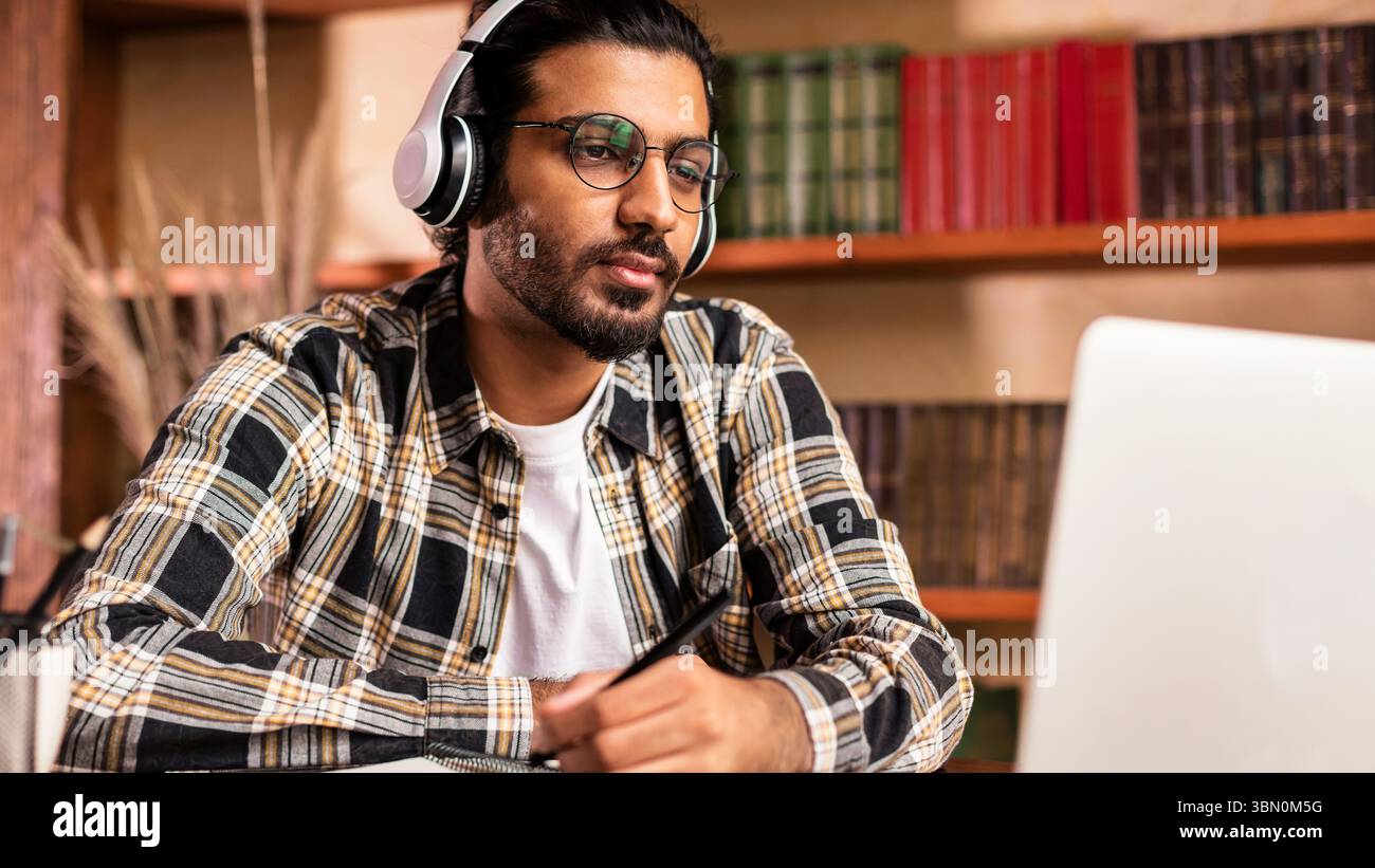 Arab Student Guy Learning Online At Laptop Sitting In Library Stock Photo