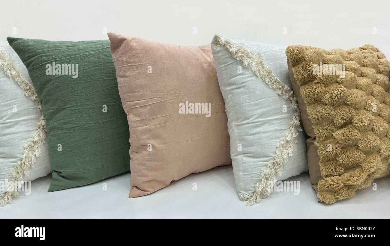 Line of decorative throw pillows in various colors and textures, perfect for cozy and stylish home decor. Stock Photo