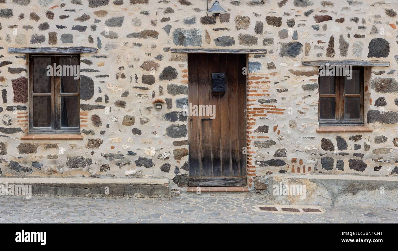 Rustic stone facade with wooden door and windows Stock Photo - Alamy