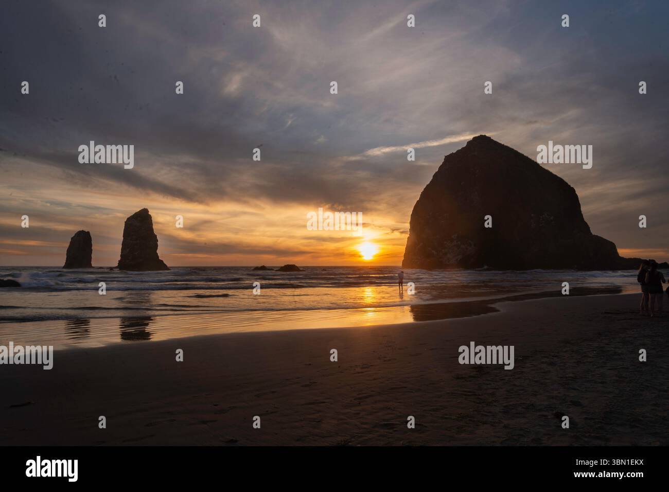 Haystack Rock at Cannon Beach during an Autum sunset. Sun silhouettes ...
