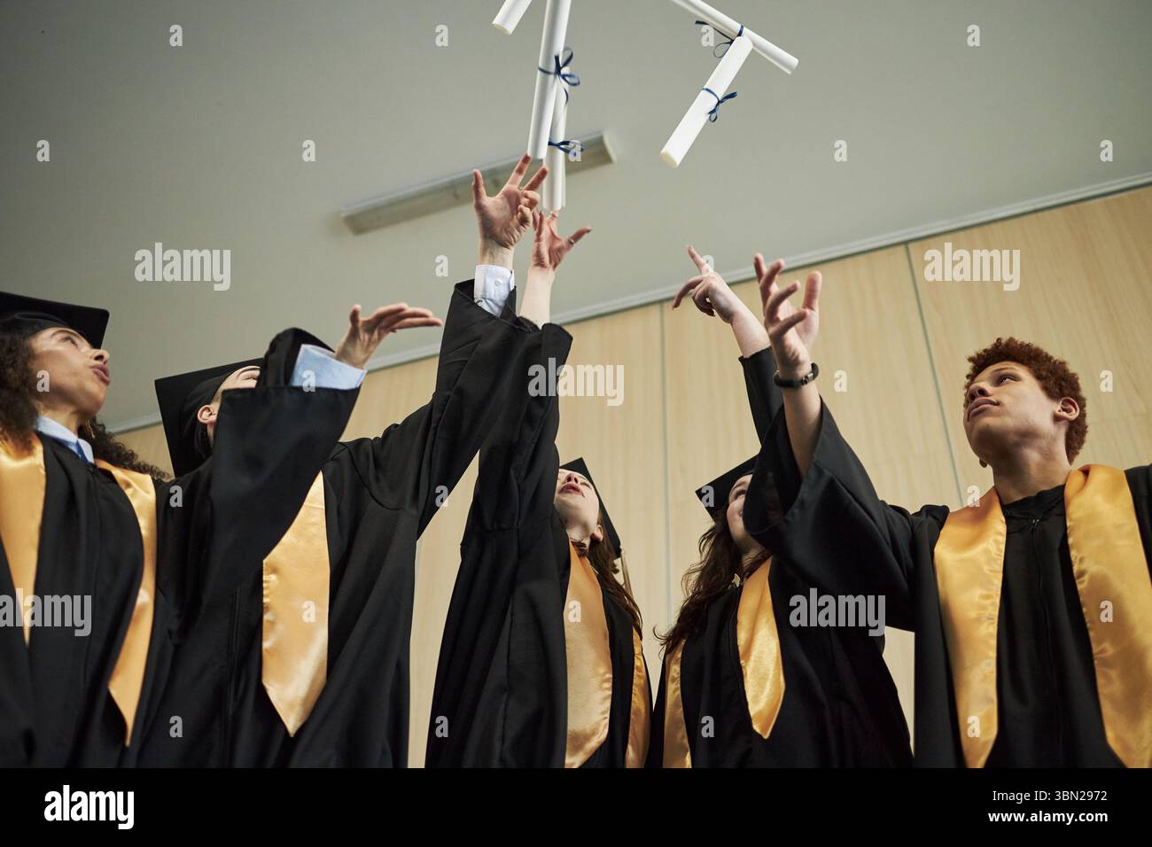 Group of diverse university young students wearing graduation gowns ...