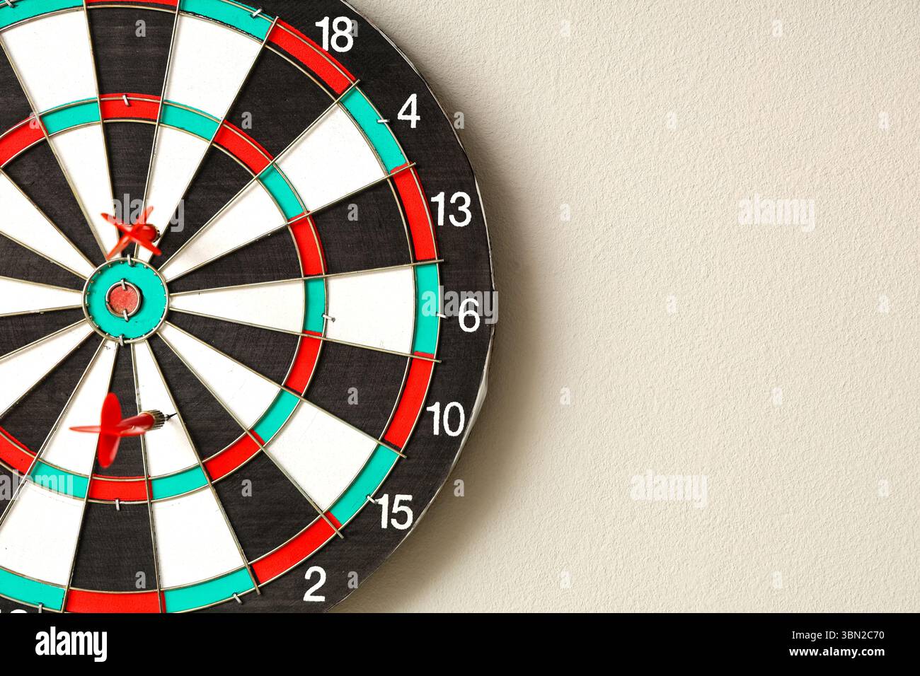 Board with darts hanging on light wall Stock Photo