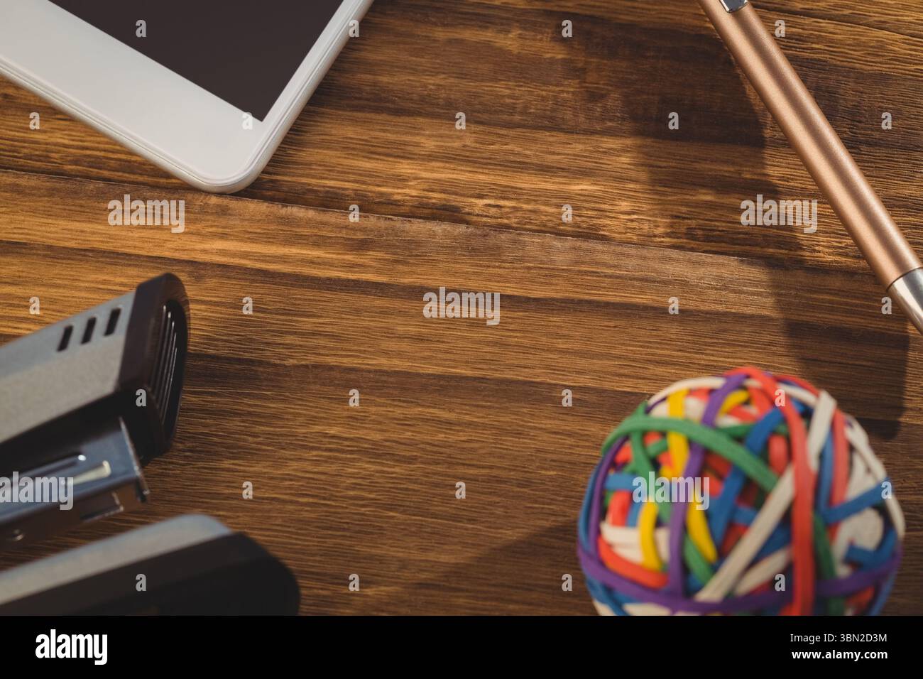 Rubber band ball with stapler on wooden table Stock Photo