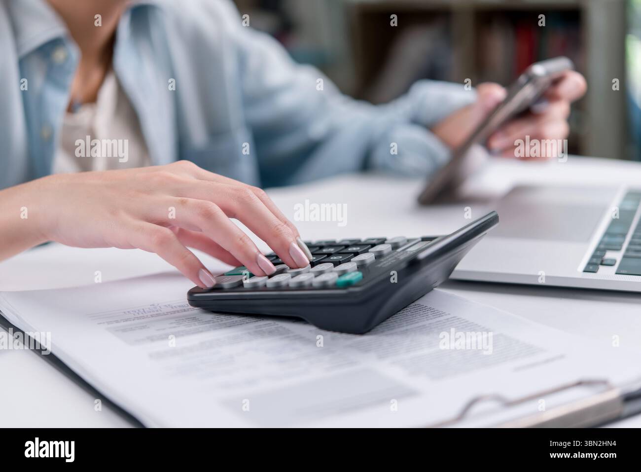 Close-up of hands working on financial documents with a calculator. Useful for finance, tax, budget, accountant, audit, and business planning concepts Stock Photo