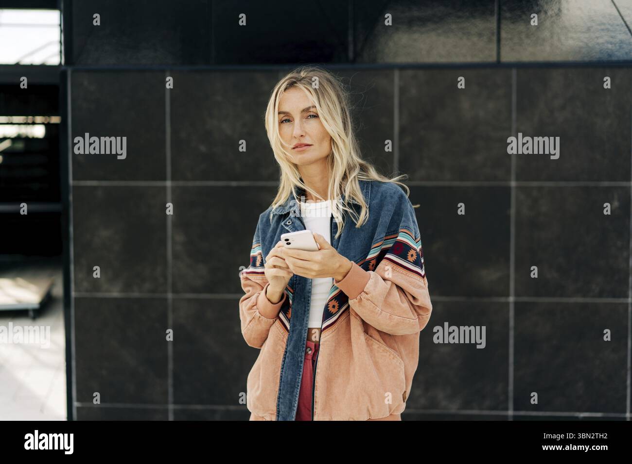 Eine junge, elegante Blondine telefoniert draussen Stock Photo