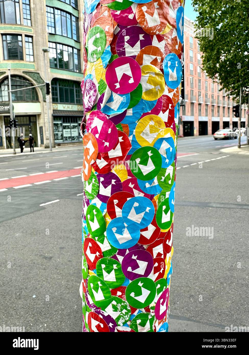 A traffic light pole covered in stickers for the Museum for Communication, has been transformed into a piece of public art in Berlin, Germany - Smartphone Captured Stock Image