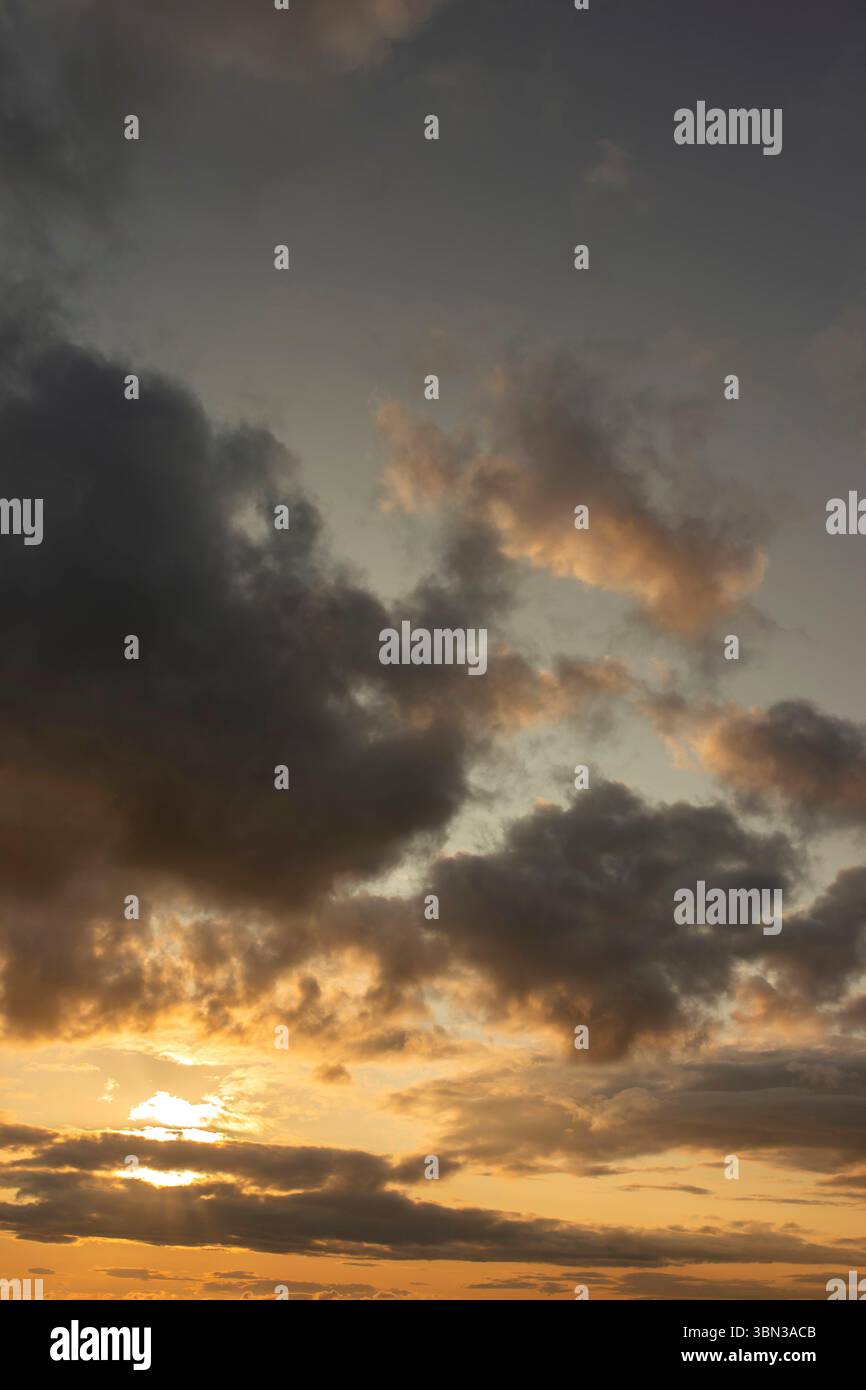 Cloudy sunset background backdrop with the sun rays breaking through the clouds. Stock Photo