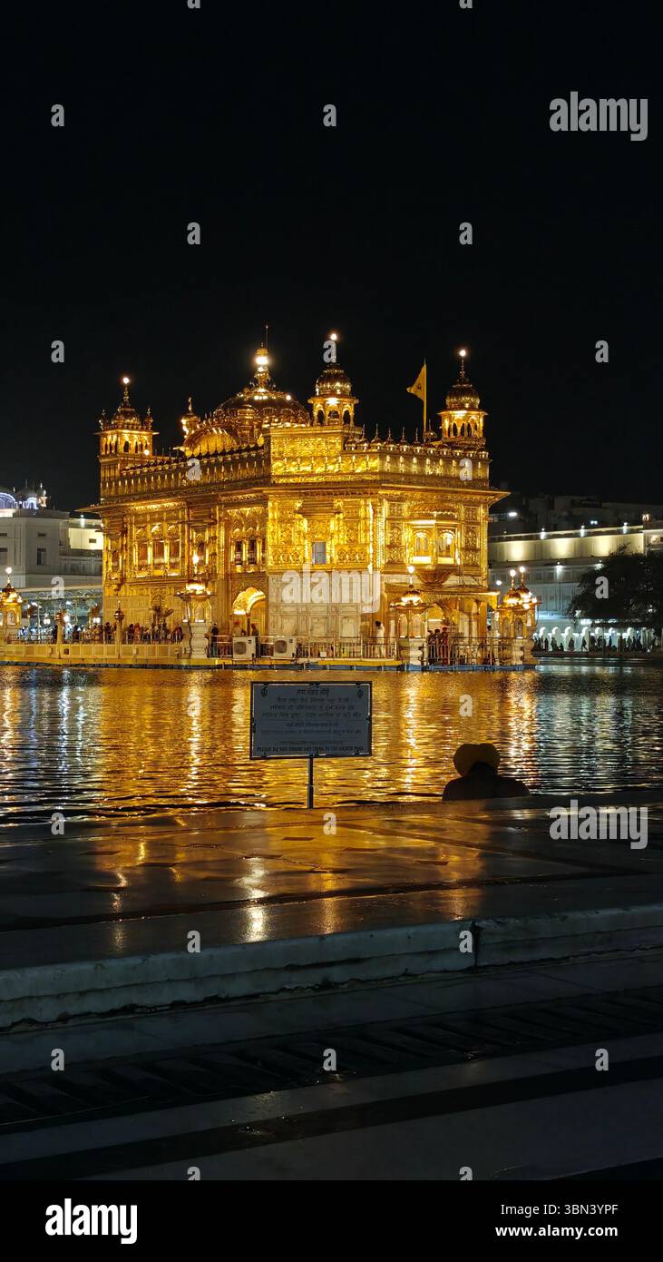 Sri Darbar Sahib Amritsar Sahib, people bathe in Amrit Sarovar  in night - Smartphone Captured Stock Image