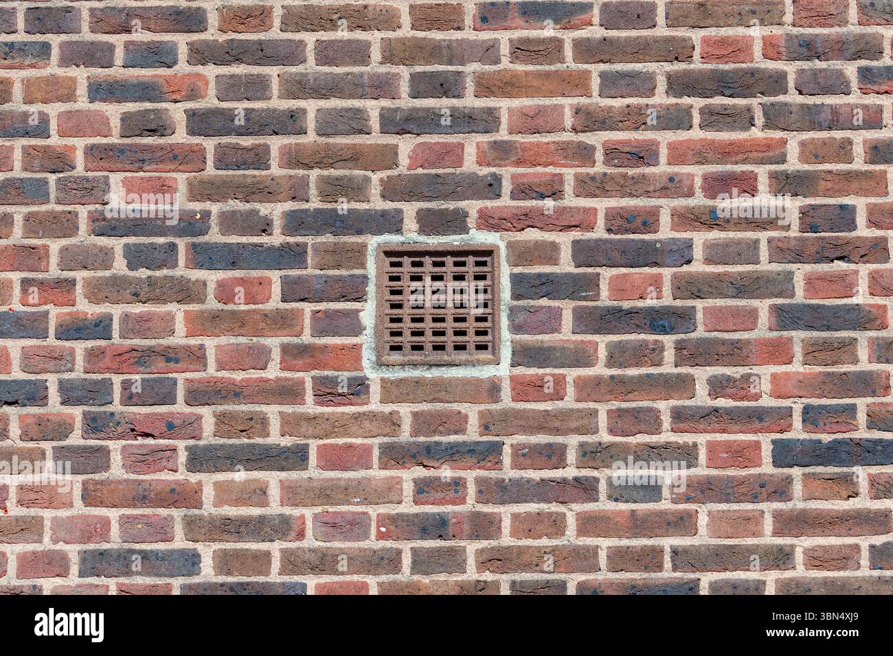 Red brick wall with a ventilation grid Stock Photo