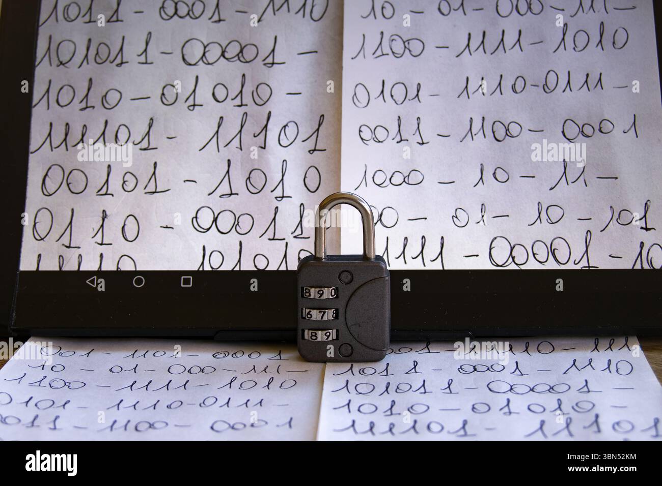close-up of a tablet screen displaying handwritten binary code, with a combination padlock resting in front, symbolizing data security Stock Photo