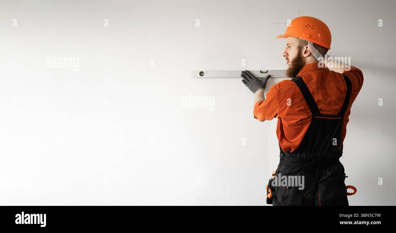 Builder wearing hardhat using spirit level measuring wall. repair ...