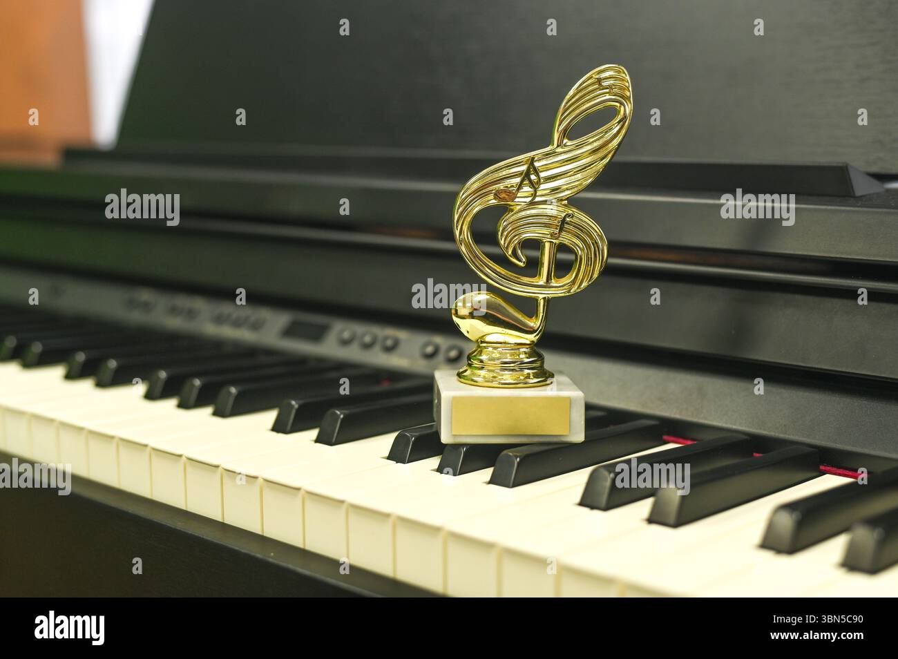 Victory trophy in form of treble clef placed on modern piano, celebrating musical excellence. The victory is a celebration of talent and perseverance Stock Photo