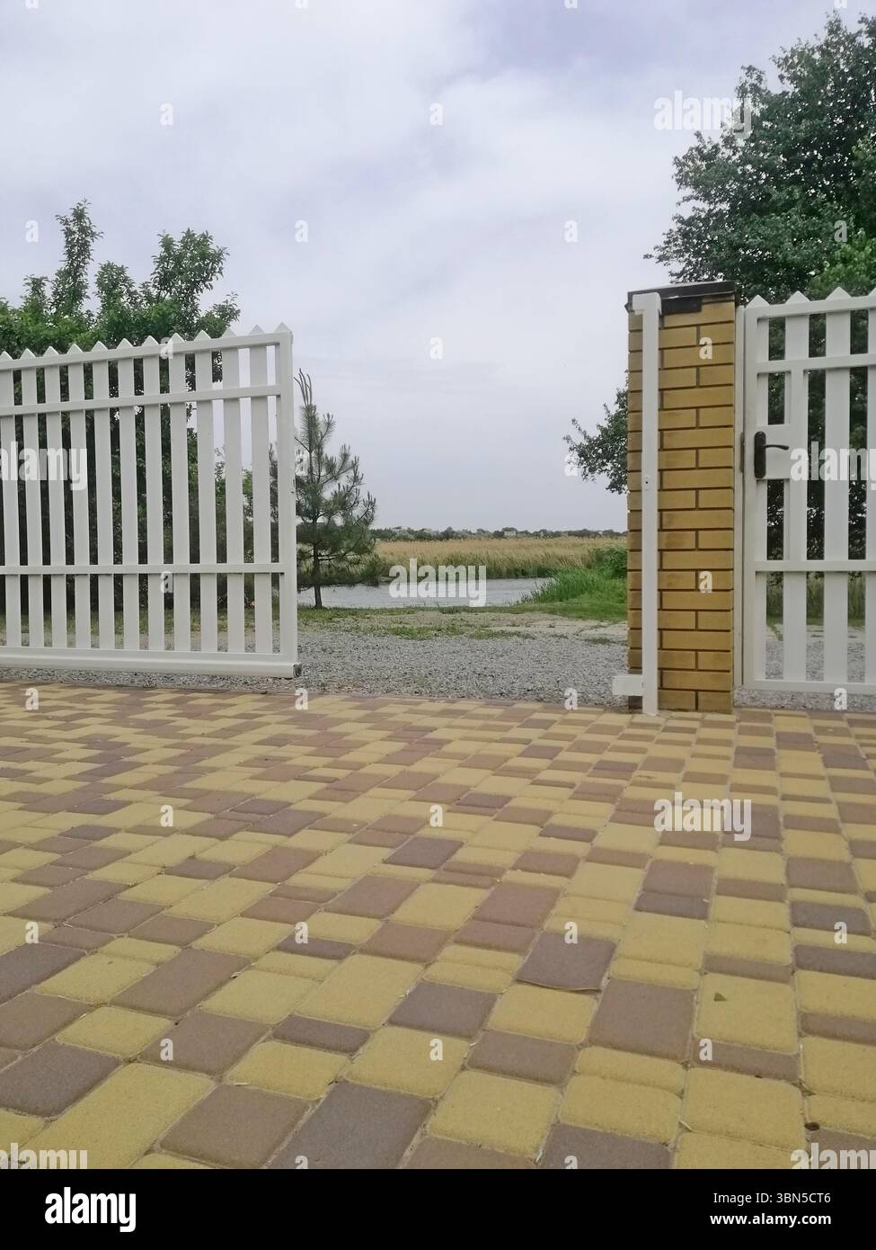 vertical photo White picket fence borders. Gravel road stretches beyond ...