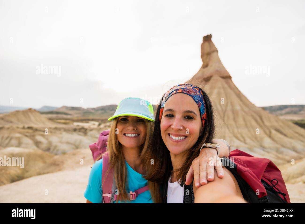 Two smiling hikers pose for a selfie in front of the iconic ...