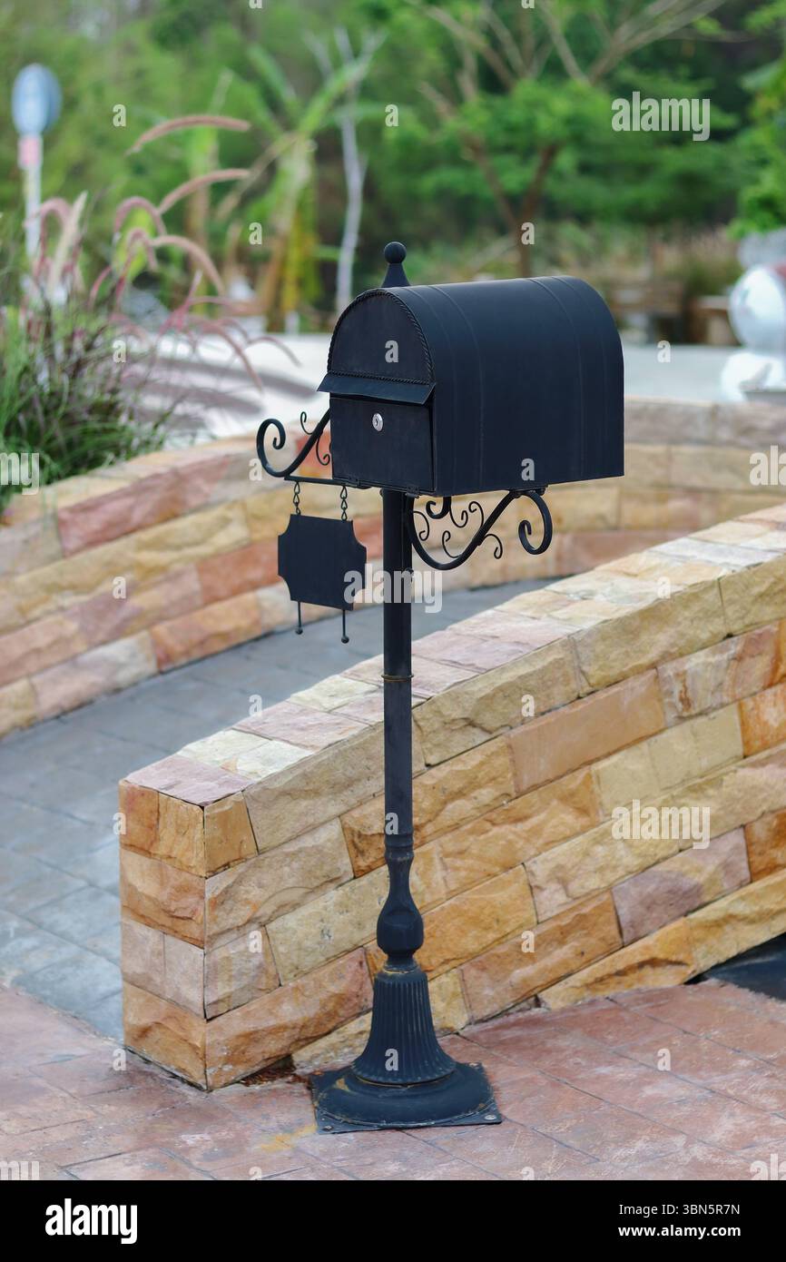 standing black metal mailbox on brick footpath. Stock Photo