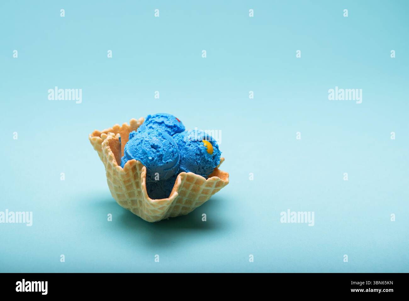 Three scoops of blue bubble gum ice cream nestled in a waffle basket ...