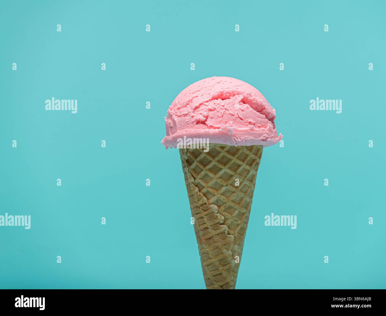 A single scoop of pink ice cream sits atop a crispy waffle cone, set ...