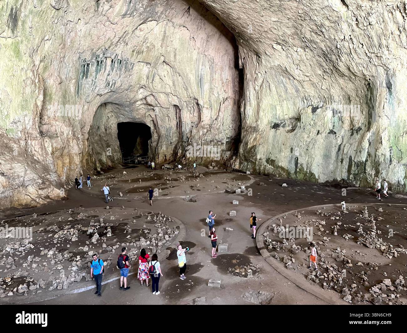 Visitors inside the vast, cathedral-like dome of Devetashka Cave in Bulgaria, a breathtaking natural wonder of the Balkan Peninsula, Eastern Europe - Smartphone Captured Stock Image