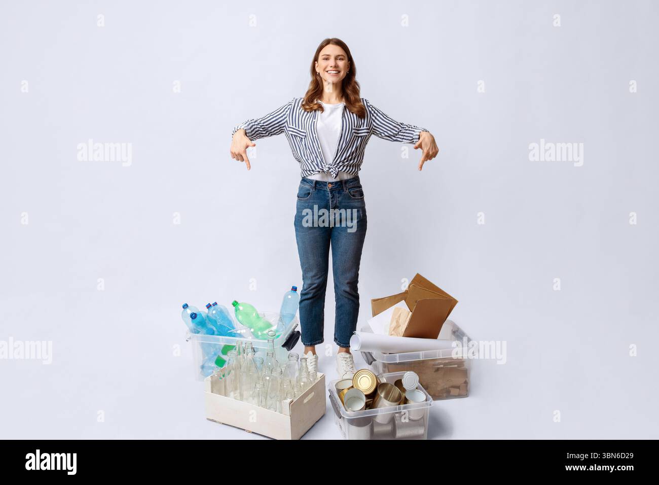 Young lady sorting waste, pointing at containers with different kind of ...