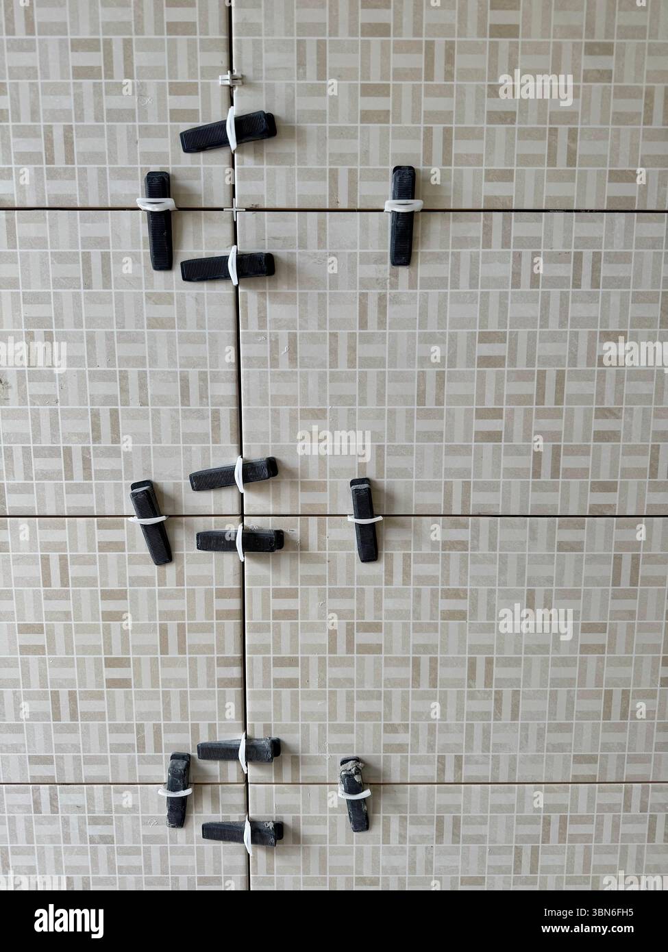 Tile leveling clips and spacers installed on wall tiles during a bathroom renovation. - Smartphone Captured Stock Image