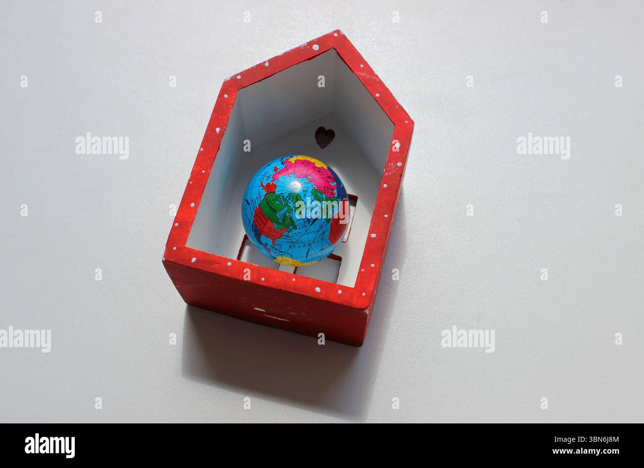 Model of the Earth with continents, oceans and travel routes inside a model house on a clean white background Stock Photo