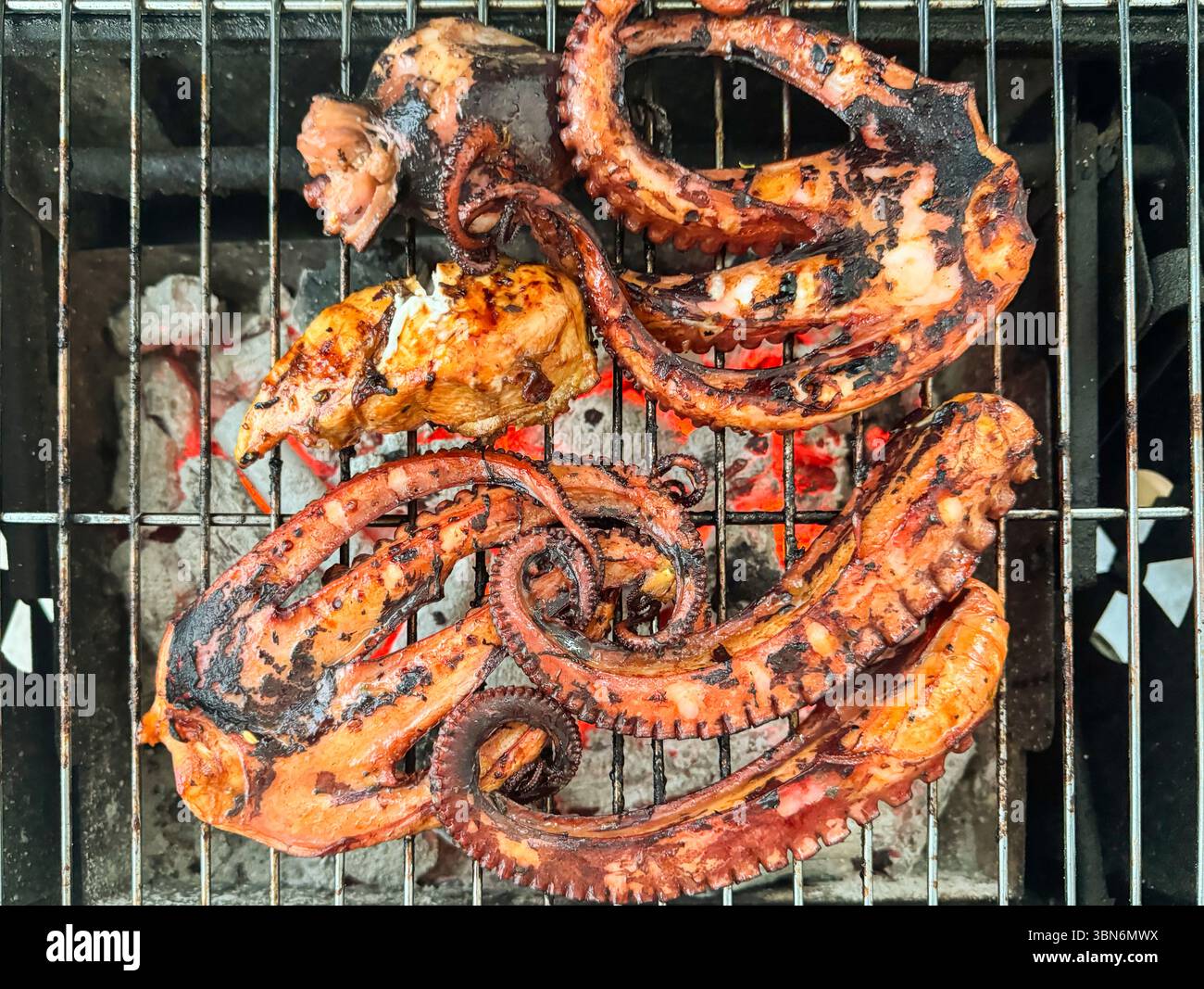 Delicious octopus and chicken are being grilled on a charcoal barbecue ...