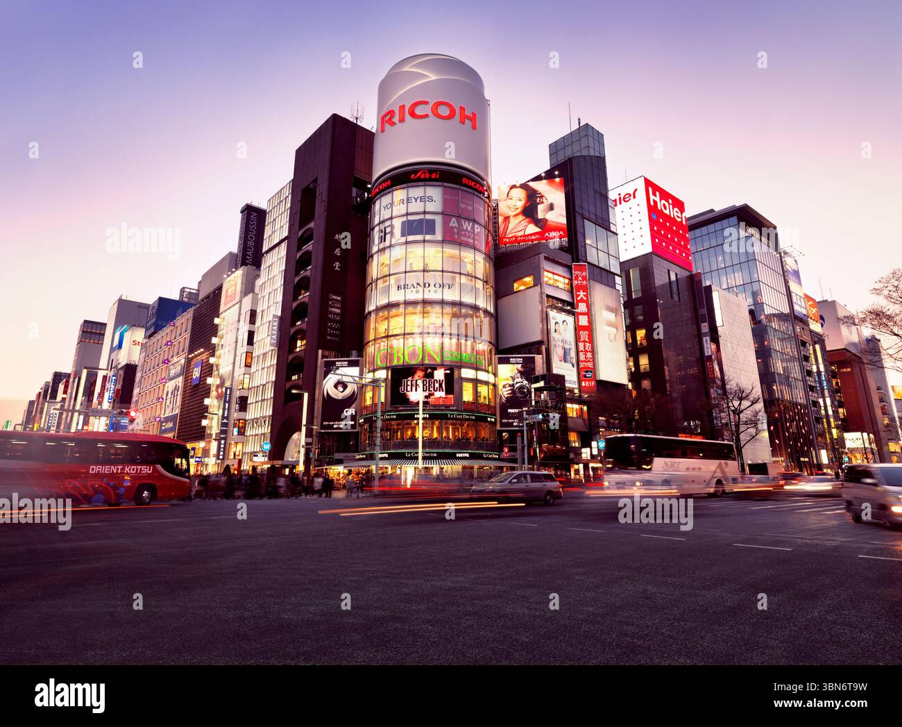 City traffic at intersection of Harumi Dori and Chou Dori. Ricoh building at dusk. Ginza, Tokyo, Japan. Stock Photo