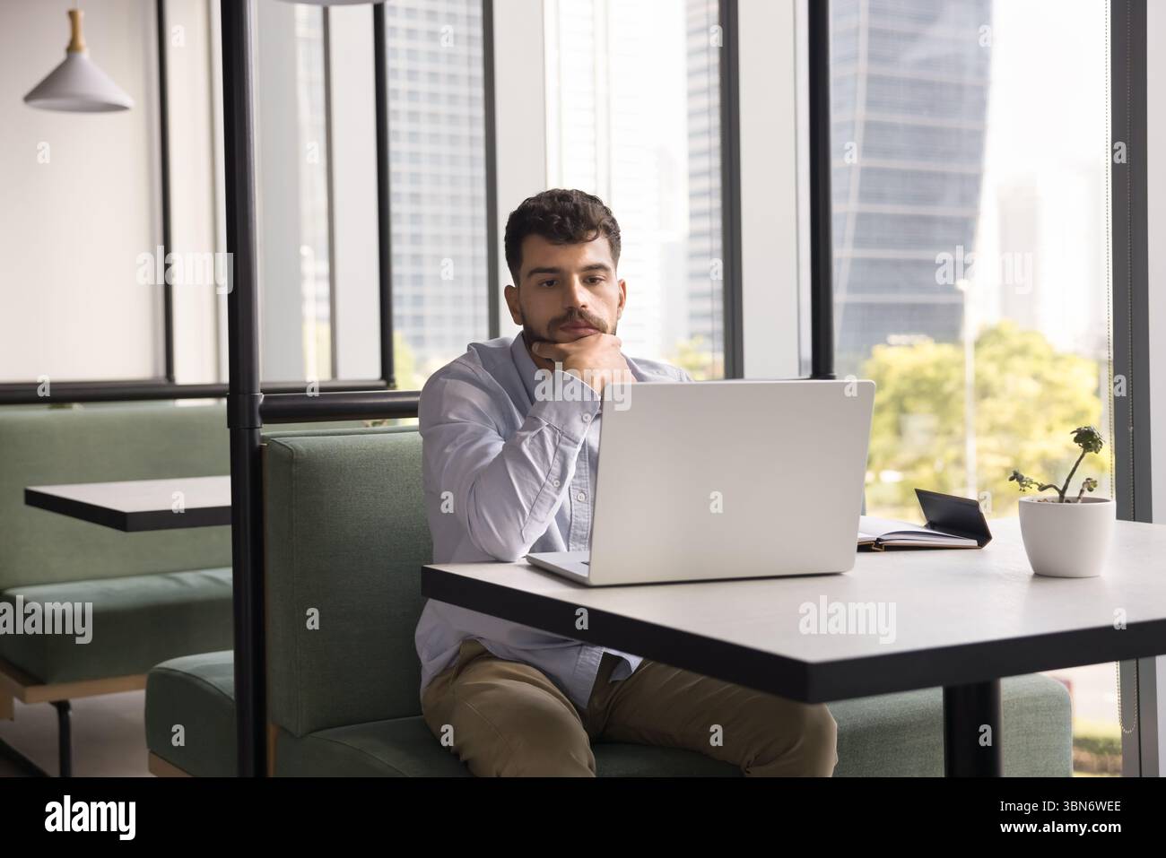 Young man sitting at table consider information on notebook screen Stock Photo