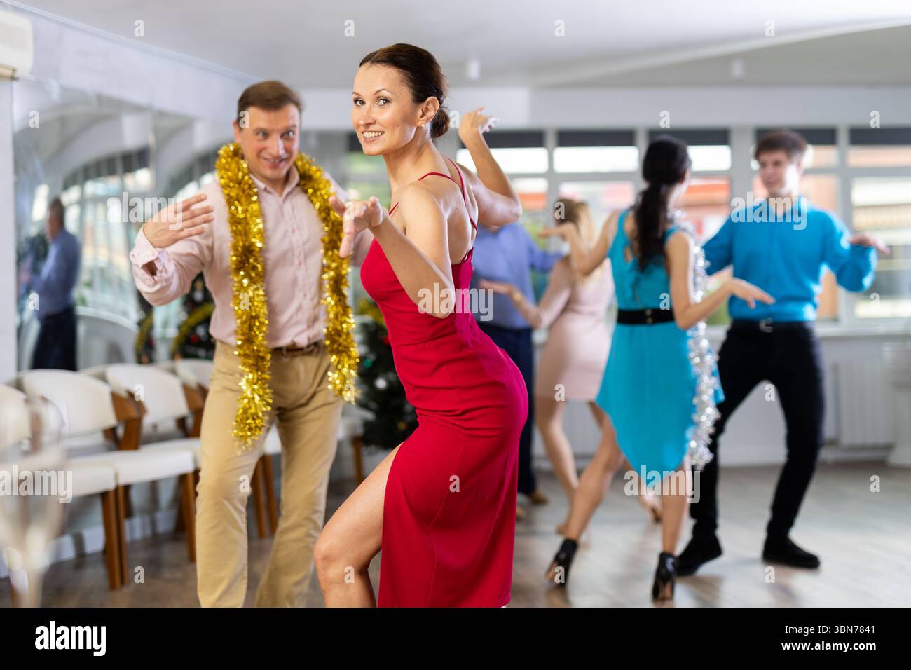 Happy brunette in red dancing twist at New Year party in dance studio Stock Photo